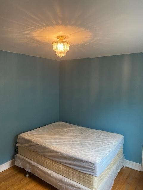 bedroom featuring wood-type flooring and a notable chandelier