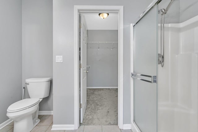 bathroom with toilet, an enclosed shower, and tile patterned flooring