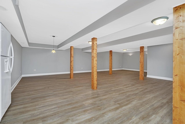 basement with dark hardwood / wood-style flooring and white refrigerator with ice dispenser