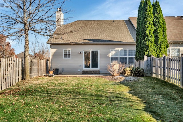 rear view of house with central AC and a lawn