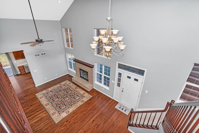 foyer entrance with ceiling fan with notable chandelier, high vaulted ceiling, and dark hardwood / wood-style floors