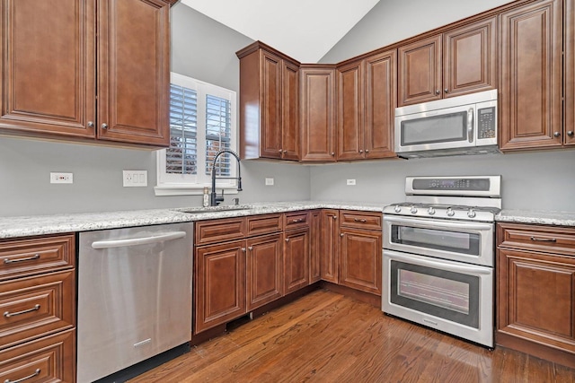 kitchen featuring appliances with stainless steel finishes, sink, dark wood-type flooring, and light stone counters