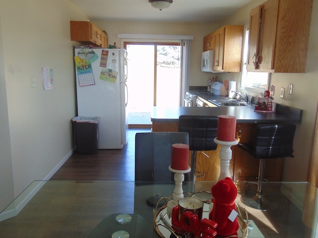 kitchen with a healthy amount of sunlight, sink, dark wood-type flooring, and white appliances