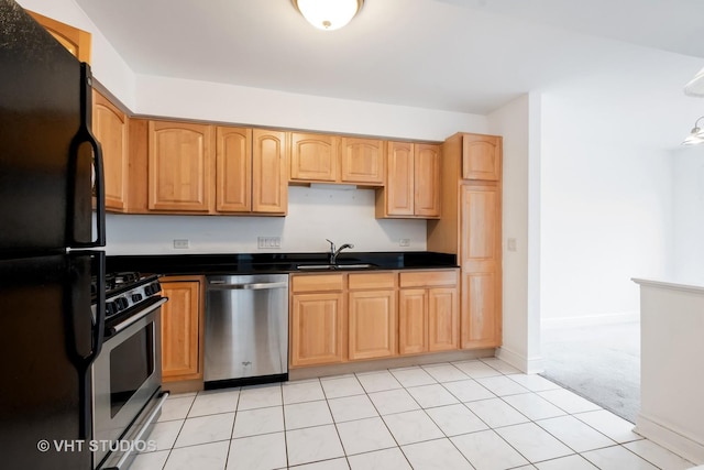 kitchen featuring dark countertops, light colored carpet, stainless steel appliances, and a sink