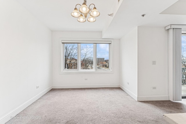 carpeted spare room featuring an inviting chandelier and baseboards