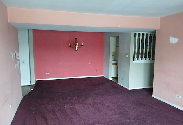 carpeted spare room featuring an inviting chandelier