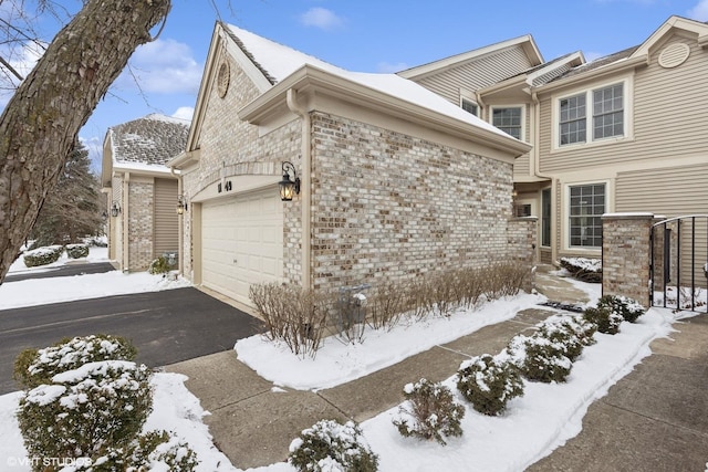 snow covered property with a garage