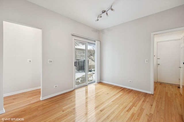 unfurnished room with track lighting and light hardwood / wood-style flooring