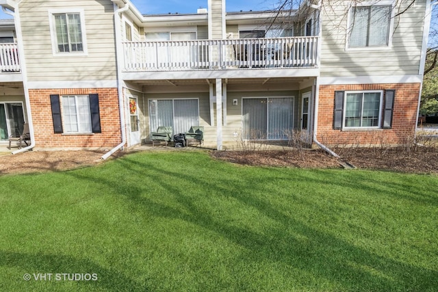 back of property featuring a balcony and a lawn