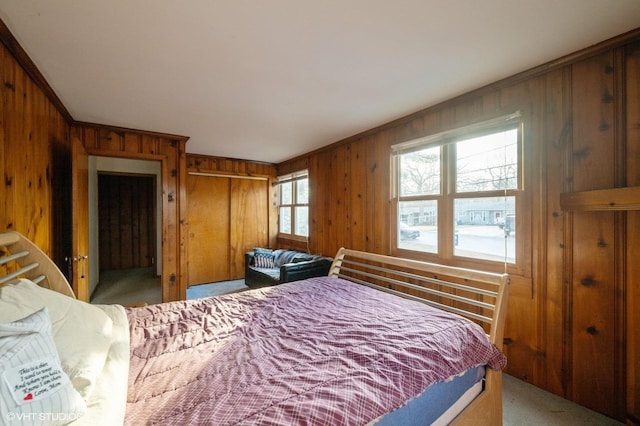 carpeted bedroom featuring ornamental molding, wooden walls, and a closet