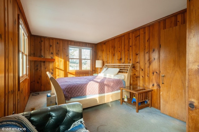 bedroom with light colored carpet and wood walls