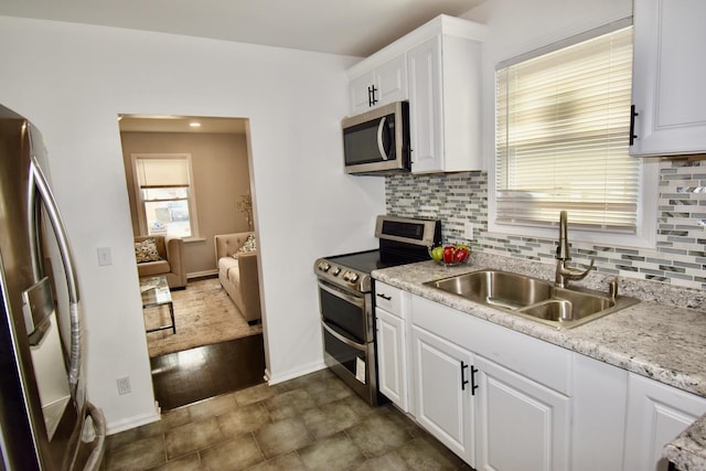 kitchen with backsplash, stainless steel appliances, sink, and white cabinets