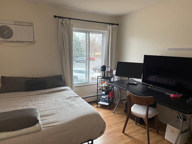 bedroom with a wall mounted air conditioner, light hardwood / wood-style floors, and baseboard heating