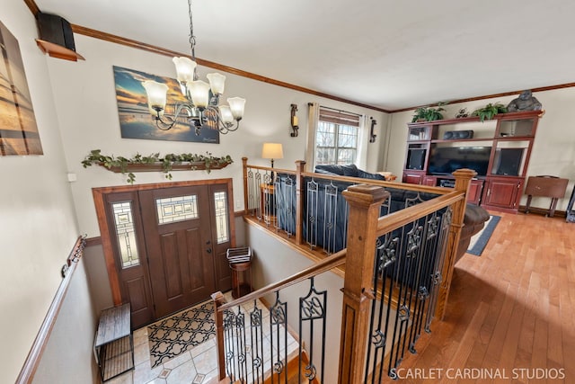 entrance foyer featuring an inviting chandelier, ornamental molding, and light wood-type flooring