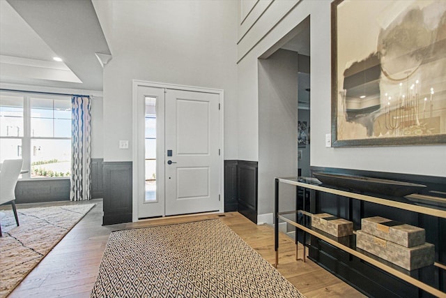 foyer entrance with wood-type flooring, ornamental molding, and a tray ceiling