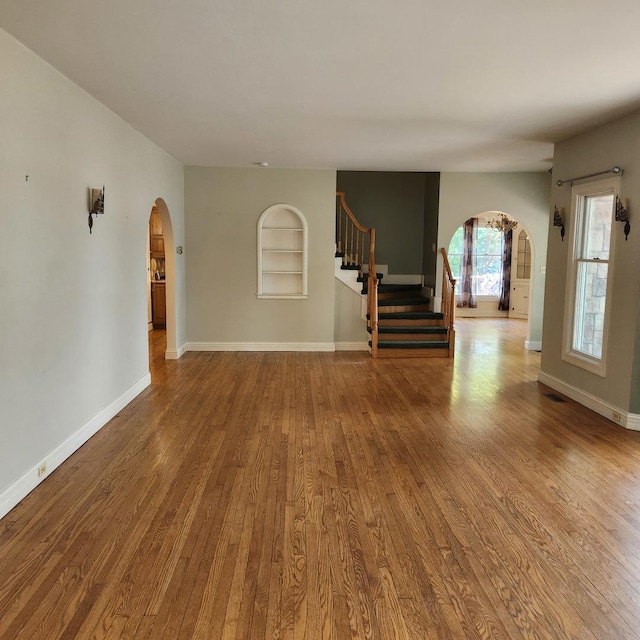 unfurnished living room with hardwood / wood-style floors and built in shelves