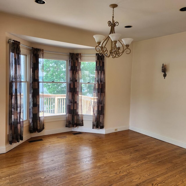 spare room featuring an inviting chandelier and wood-type flooring