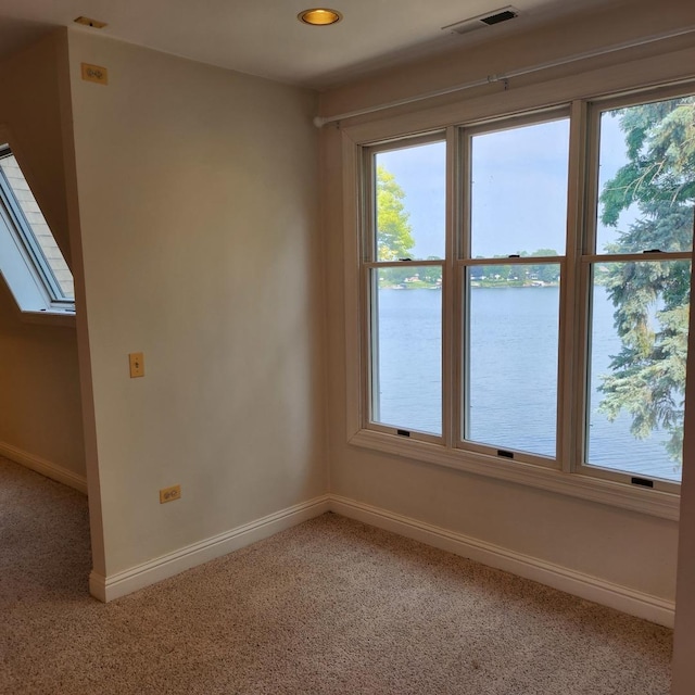 unfurnished room with a water view, carpet floors, and a skylight