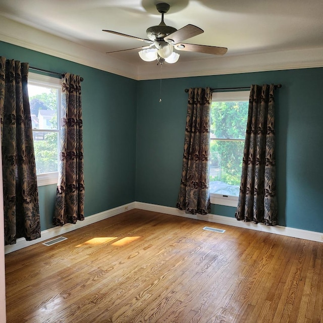 spare room featuring wood-type flooring, ornamental molding, and ceiling fan