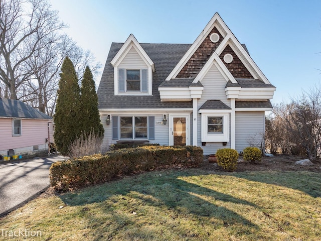 view of front of property with a front lawn and a shingled roof