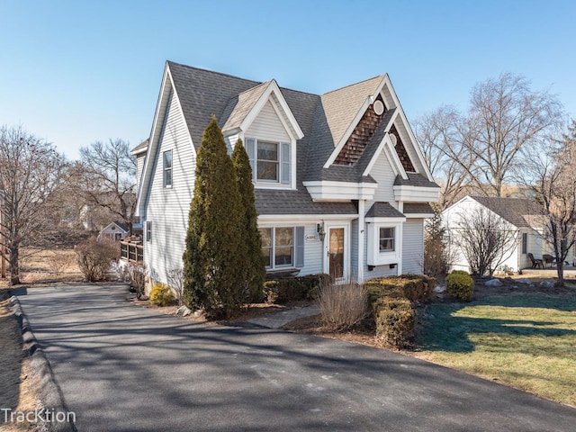 view of front facade featuring roof with shingles and a front yard