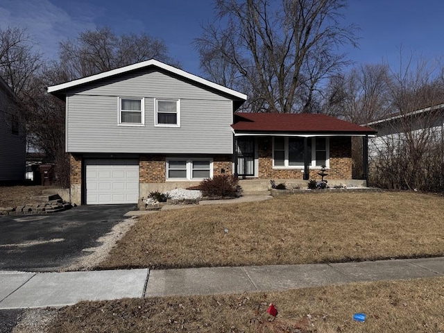 tri-level home with a garage, a front lawn, and covered porch