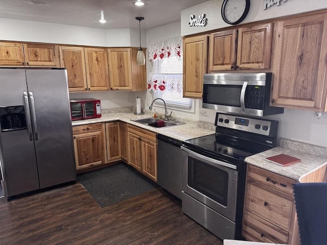 kitchen with dark hardwood / wood-style floors, appliances with stainless steel finishes, decorative light fixtures, and sink