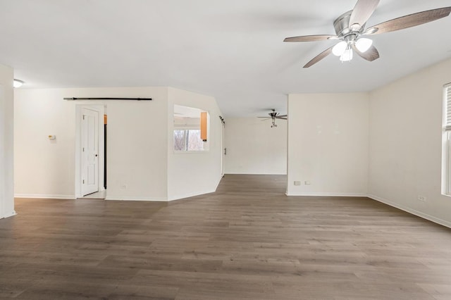 unfurnished room with hardwood / wood-style flooring, a barn door, and ceiling fan