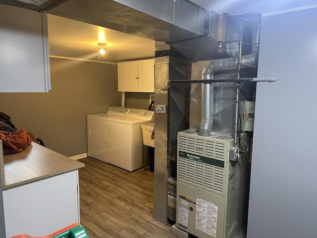 clothes washing area with cabinets, washing machine and clothes dryer, and hardwood / wood-style floors