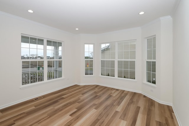 empty room featuring ornamental molding, a healthy amount of sunlight, and hardwood / wood-style floors