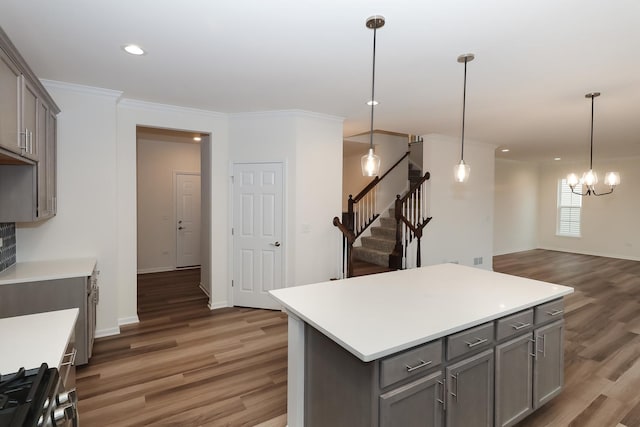 kitchen featuring crown molding, a kitchen island, hanging light fixtures, and gray cabinetry