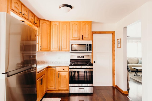 kitchen with fridge, dark hardwood / wood-style flooring, light brown cabinetry, and stainless steel gas range oven