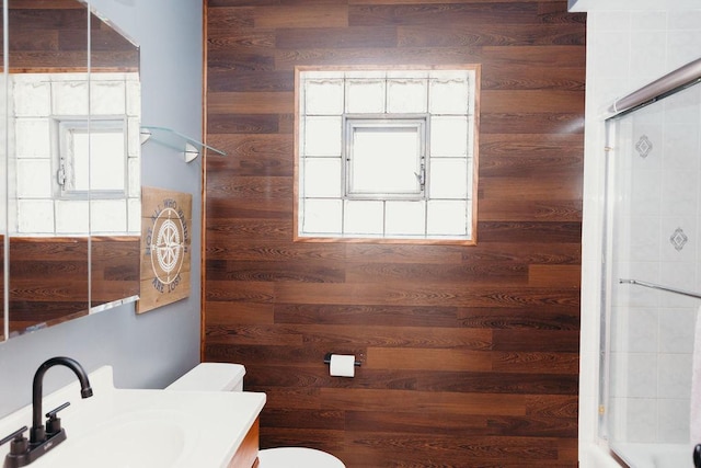 bathroom with vanity, wooden walls, and toilet