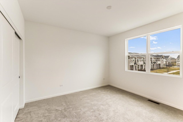 unfurnished bedroom with light carpet and a closet