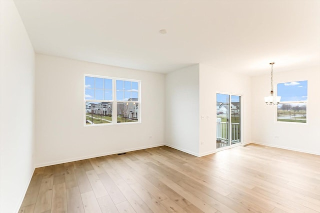 unfurnished room with an inviting chandelier and light hardwood / wood-style floors