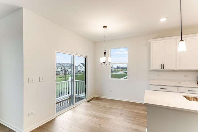 kitchen with white cabinetry, pendant lighting, and light hardwood / wood-style floors