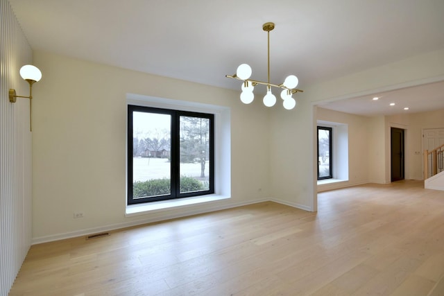 spare room with light hardwood / wood-style flooring and a chandelier