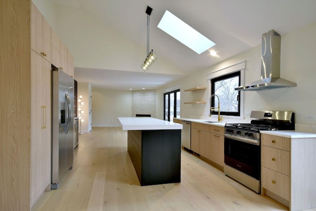 kitchen featuring sink, decorative light fixtures, a center island, appliances with stainless steel finishes, and wall chimney range hood