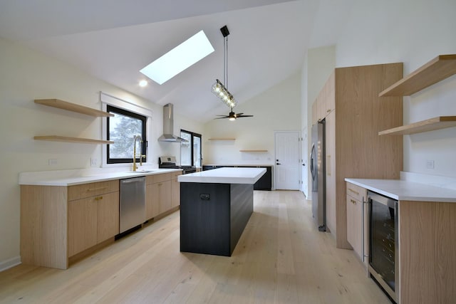 kitchen with pendant lighting, wall chimney range hood, appliances with stainless steel finishes, a kitchen island, and beverage cooler