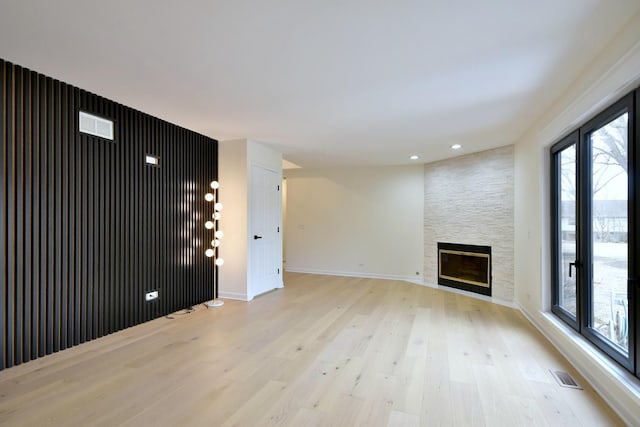 unfurnished living room featuring light hardwood / wood-style floors and a large fireplace