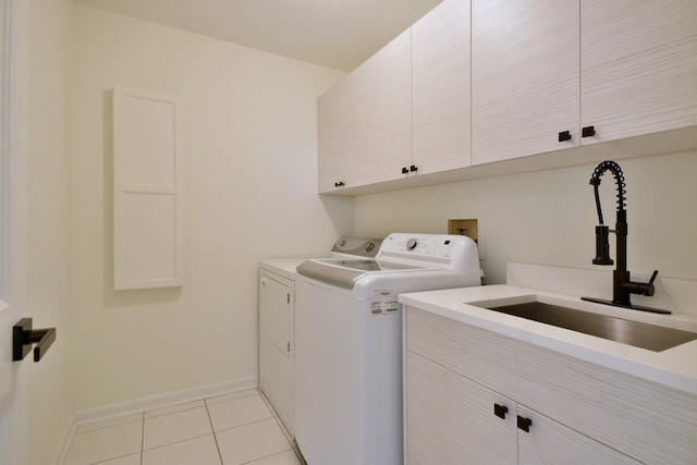 clothes washing area with cabinets, sink, light tile patterned floors, and washing machine and clothes dryer