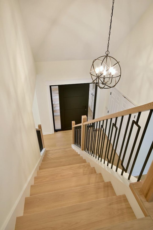 stairs with hardwood / wood-style floors and an inviting chandelier