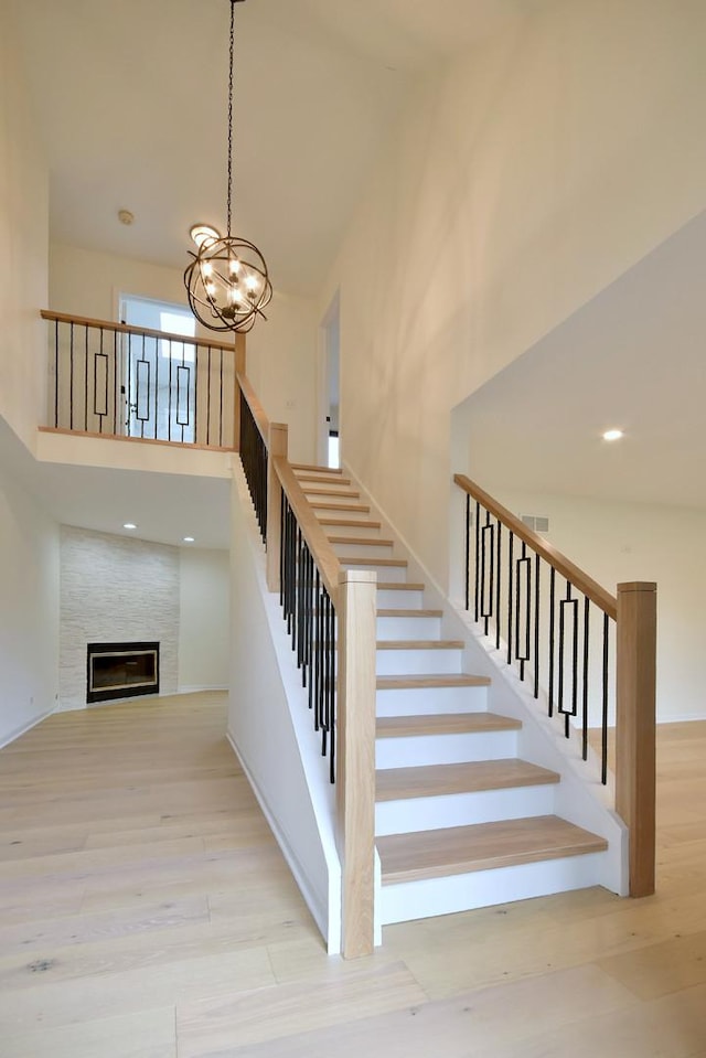 stairway featuring a notable chandelier, a towering ceiling, and wood-type flooring