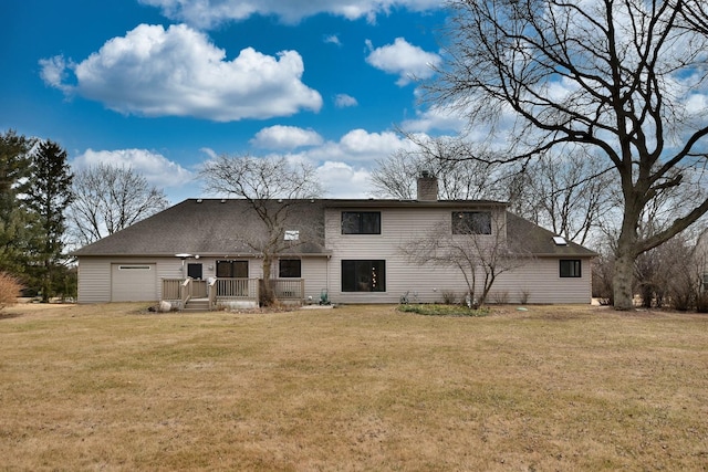 rear view of house featuring a garage and a lawn