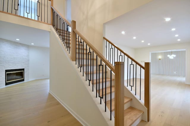 stairway featuring hardwood / wood-style flooring, a high ceiling, and a fireplace