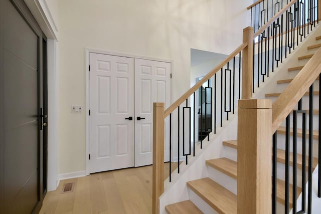 foyer entrance featuring a towering ceiling and light hardwood / wood-style flooring