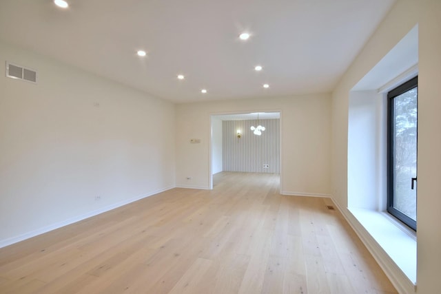 unfurnished room featuring an inviting chandelier and light hardwood / wood-style floors