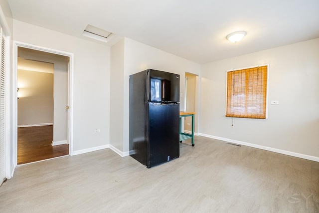 unfurnished living room with attic access, visible vents, light wood-style flooring, and baseboards