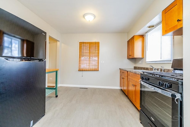 kitchen featuring visible vents, baseboards, brown cabinets, light wood-type flooring, and black appliances