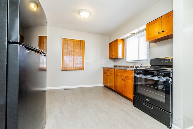 kitchen with baseboards, brown cabinets, and black appliances